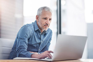 Mann sitzt vor Laptop
